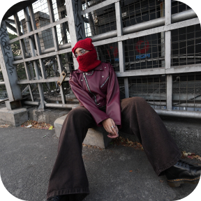 ARTA sitting outside in a red mask and burgundy jacket